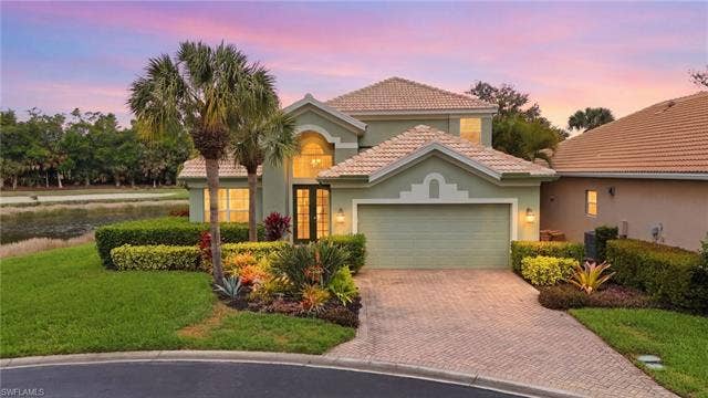 17801 Modena Rd, Miromar Lakes, FL 33913 Mediterranean / spanish-style home featuring stucco siding, a garage, a front yard, and a tiled roof