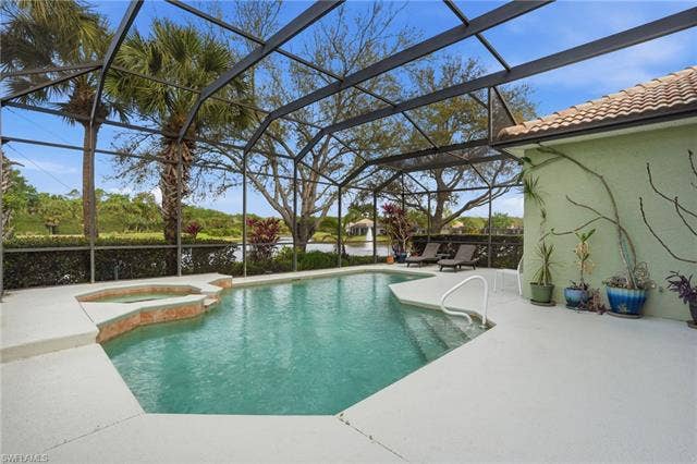 17801 Modena Rd, Miromar Lakes, FL 33913 Combined pool / hot tub featuring a patio area, glass enclosure, and a sunroom
