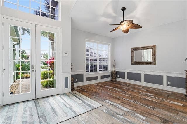 17801 Modena Rd, Miromar Lakes, FL 33913 Doorway to outside with a decorative wall, french doors, hardwood / wood-style flooring, a ceiling fan, and wainscoting