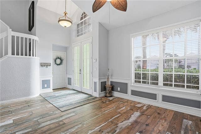 17801 Modena Rd, Miromar Lakes, FL 33913 Foyer featuring french doors, light wood-style flooring, ceiling fan, wainscoting, and vaulted ceiling
