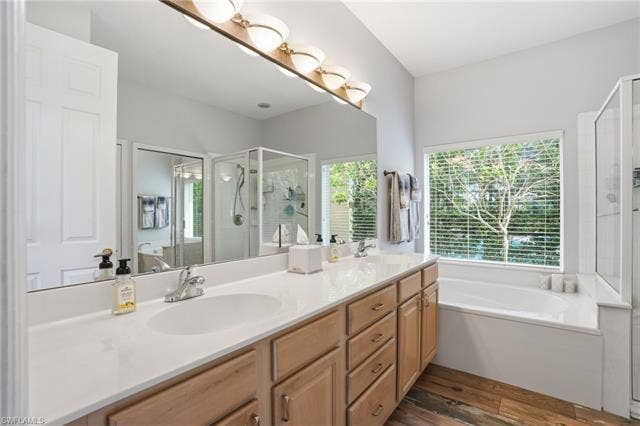17801 Modena Rd, Miromar Lakes, FL 33913 Bathroom featuring a garden tub, a shower stall, double vanity, and dark wood-style floors