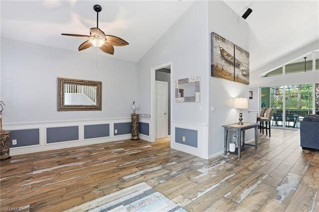 17801 Modena Rd, Miromar Lakes, FL 33913 Living room with ceiling fan, lofted ceiling, light wood finished floors, a decorative wall, and a wainscoted wall