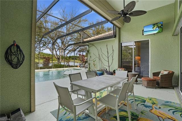 17801 Modena Rd, Miromar Lakes, FL 33913 View of patio / terrace featuring a sunroom, an outdoor pool, a lanai, ceiling fan, and outdoor dining space