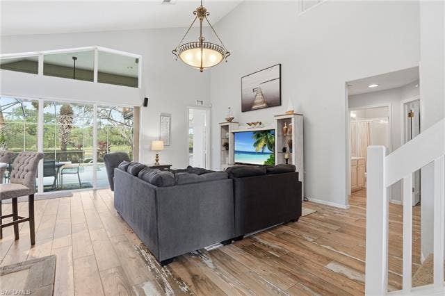 17801 Modena Rd, Miromar Lakes, FL 33913 Living area featuring a sunroom, light wood-type flooring, and lofted ceiling