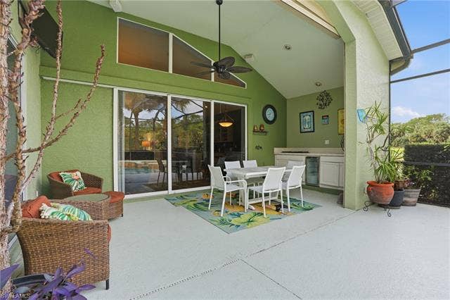 17801 Modena Rd, Miromar Lakes, FL 33913 View of patio / terrace with an outdoor kitchen / dining area, a lanai, wine cooler, ceiling fan, and a sunroom