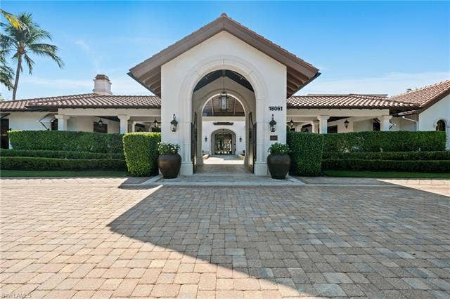 17801 Modena Rd, Miromar Lakes, FL 33913 View of exterior entry featuring stucco siding and a chimney