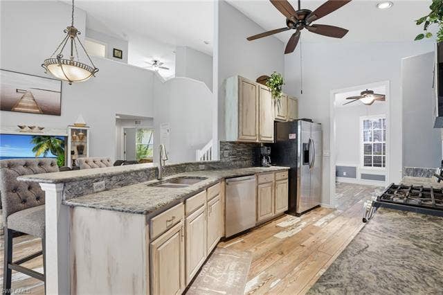17801 Modena Rd, Miromar Lakes, FL 33913 Kitchen featuring light wood finish cabinets, light stone countertops, ceiling fan, open floor plan, and vaulted ceiling