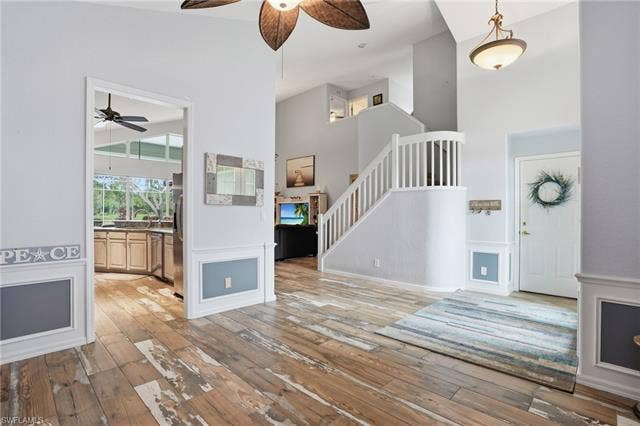 17801 Modena Rd, Miromar Lakes, FL 33913 Unfurnished living room with a ceiling fan, a high ceiling, and light wood-style flooring