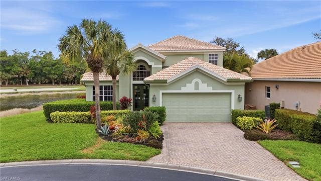 17801 Modena Rd, Miromar Lakes, FL 33913 Mediterranean / spanish-style home with stucco siding, a garage, a front lawn, a tiled roof, and decorative driveway