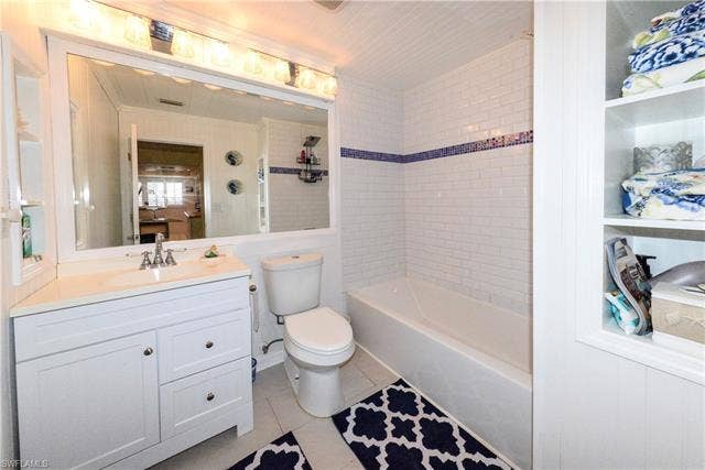 22161 Tallwood Ct, #706, Estero, FL 33928 Bathroom featuring a white vanity with an integrated sink, a large mirror, and white subway tile in the tub/shower surround