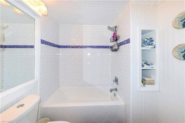 22161 Tallwood Ct, #706, Estero, FL 33928 Tub/shower combination featuring white subway tile surround with a blue mosaic accent stripe