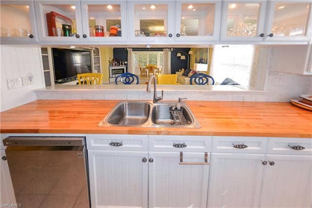 22161 Tallwood Ct, #706, Estero, FL 33928 Kitchen featuring a stainless steel double basin sink, light wood-finish countertops, and white paneled cabinetry with dark hardware
