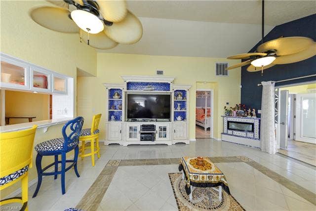 22161 Tallwood Ct, #706, Estero, FL 33928 Spacious living area featuring high vaulted ceilings, multiple ceiling fans, and a built-in media center