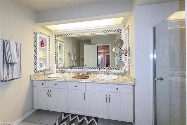 22161 Tallwood Ct, #706, Estero, FL 33928 Bathroom featuring a double vanity with granite countertop, two undermount sinks, and white cabinetry