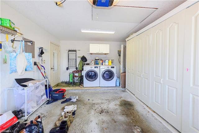 22161 Tallwood Ct, #706, Estero, FL 33928 Garage space featuring a washer and dryer, upper cabinetry, a utility door, and extensive built-in storage solutions