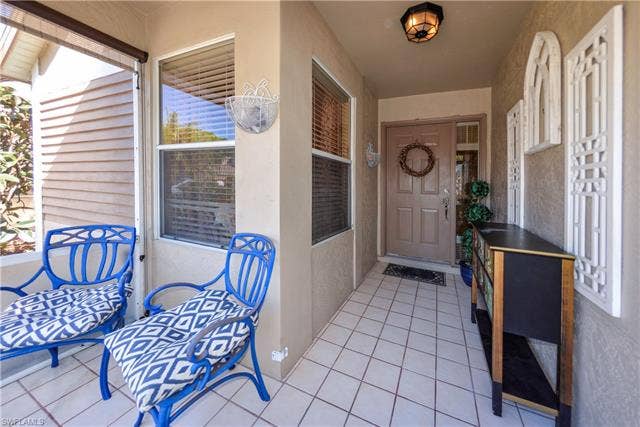 22161 Tallwood Ct, #706, Estero, FL 33928 Covered porch entry featuring square tile flooring and a solid paneled door with a sidelight window