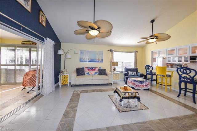 22161 Tallwood Ct, #706, Estero, FL 33928 Spacious living area featuring tile flooring with decorative inlay, vaulted ceilings, and dual ceiling fans with integrated lighting