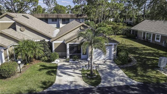 22161 Tallwood Ct, #706, Estero, FL 33928 Property exterior featuring a single-car garage, concrete driveway, and mature landscaping