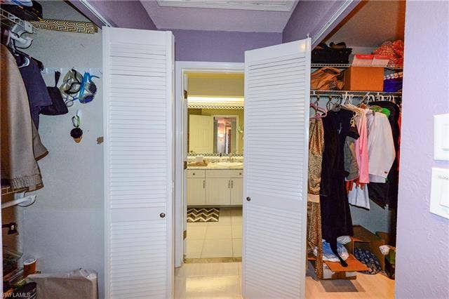 22161 Tallwood Ct, #706, Estero, FL 33928 Louvered bifold doors open to a bathroom featuring a double vanity with an integrated mirror, surrounded by decorative trim