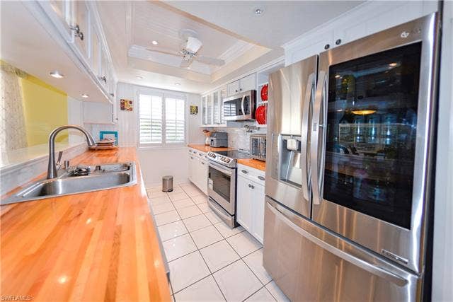 22161 Tallwood Ct, #706, Estero, FL 33928 Modern kitchen featuring stainless steel appliances, wood-finish countertops, white cabinetry, a built-in microwave, and recessed lighting