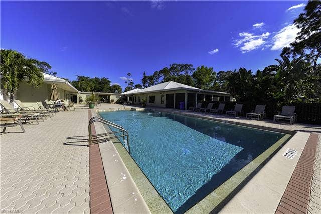 22161 Tallwood Ct, #706, Estero, FL 33928 Outdoor swimming pool featuring a ladder entry, paver decking, and surrounding tropical foliage