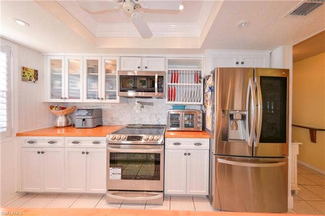 22161 Tallwood Ct, #706, Estero, FL 33928 Modern kitchen featuring white cabinetry, stainless steel appliances, marble-look backsplash, wood-finish countertops, and recessed lighting