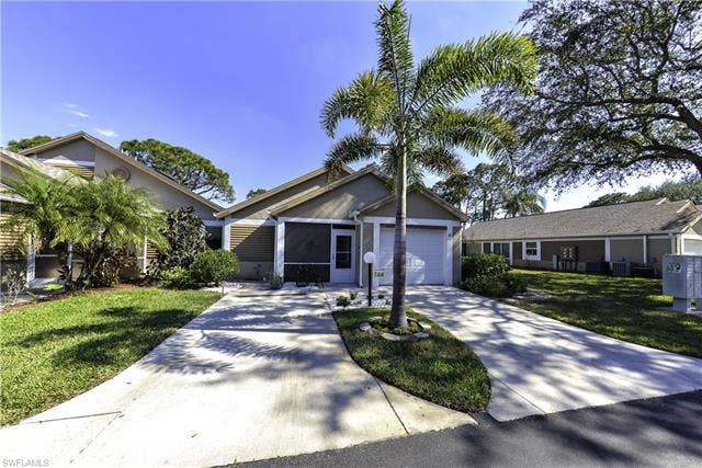 22161 Tallwood Ct, #706, Estero, FL 33928 Concrete driveway leading to a single-car garage and screened entry