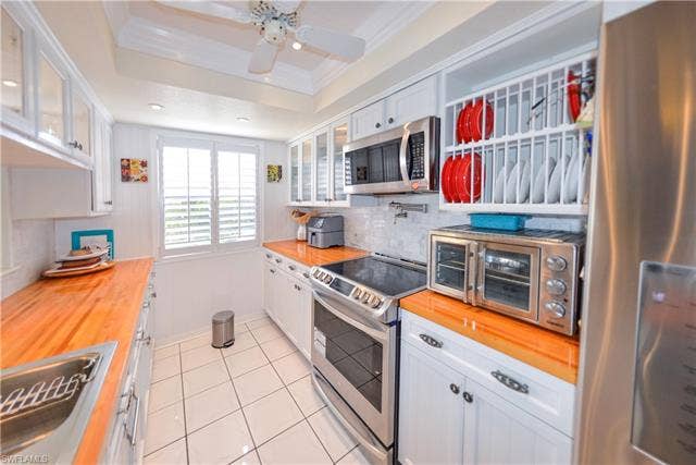 22161 Tallwood Ct, #706, Estero, FL 33928 Bright kitchen featuring white cabinetry, wood-finish countertops, stainless steel appliances, and tile flooring