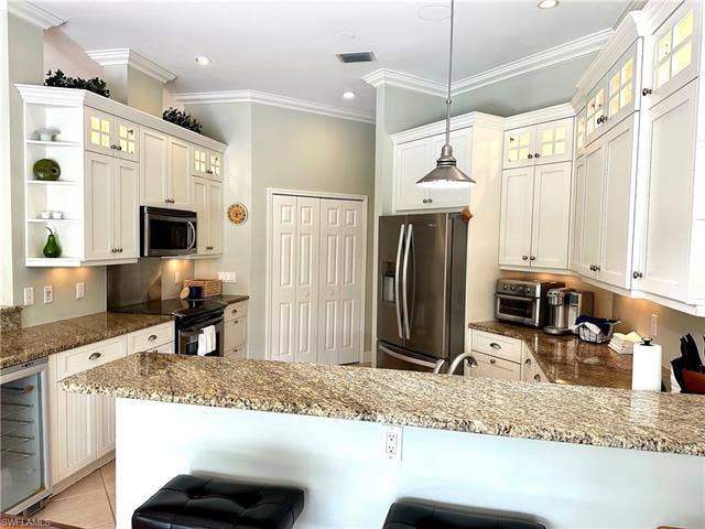 12654 Buttonbush Pl, Bonita Springs, FL 34135 The kitchen features include stainless steel, granite, a wine fridge, a large pantry, and accent lighting.