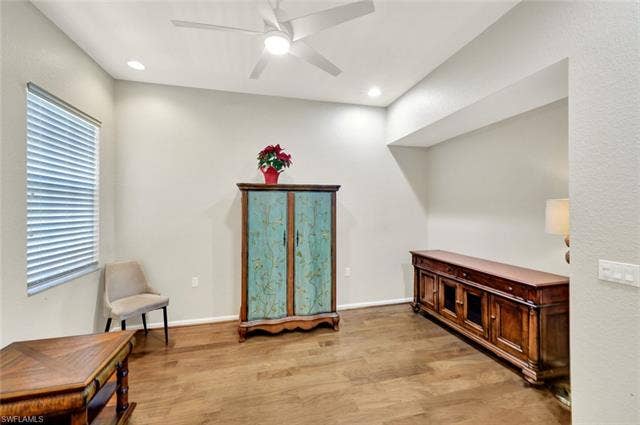 10060 Valiant Ct, #202, Miromar Lakes, FL 33913 Spacious room featuring wood-finish flooring, a contemporary ceiling fan, recessed lighting, a large window with blinds, and light-toned walls