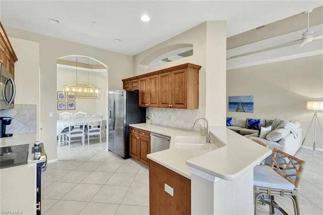 10060 Valiant Ct, #202, Miromar Lakes, FL 33913 Kitchen featuring wood cabinetry, stainless steel appliances, white countertops, and a subway tile backsplash