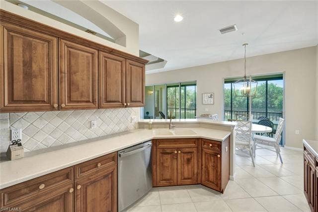 10060 Valiant Ct, #202, Miromar Lakes, FL 33913 Kitchen featuring wood-finish cabinetry, solid surface countertops, diagonal tile backsplash, stainless steel dishwasher, and recessed lighting