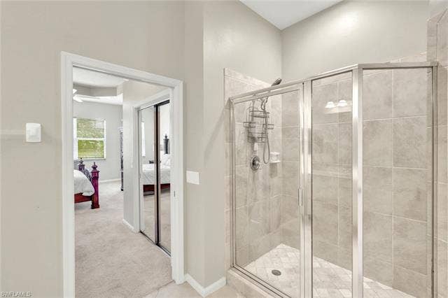10060 Valiant Ct, #202, Miromar Lakes, FL 33913 Walk-in shower featuring glass enclosure and light-toned tile surround