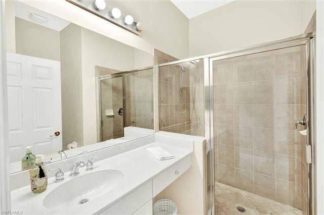 10060 Valiant Ct, #202, Miromar Lakes, FL 33913 Bathroom featuring a white vanity with an integrated sink, chrome faucet, and expansive wall-mounted mirror