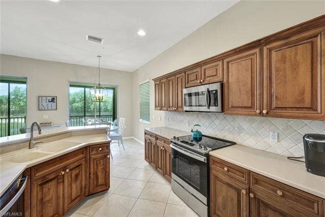 10060 Valiant Ct, #202, Miromar Lakes, FL 33913 Kitchen featuring wood cabinetry, light-toned countertops, a stainless steel microwave, and a stainless steel range with a flat cooktop