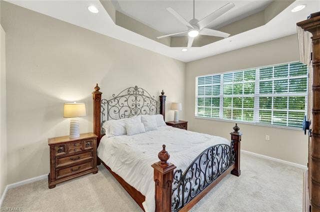 10060 Valiant Ct, #202, Miromar Lakes, FL 33913 Bedroom featuring a tray ceiling, recessed lighting, ceiling fan, large window with blinds, and neutral carpet flooring