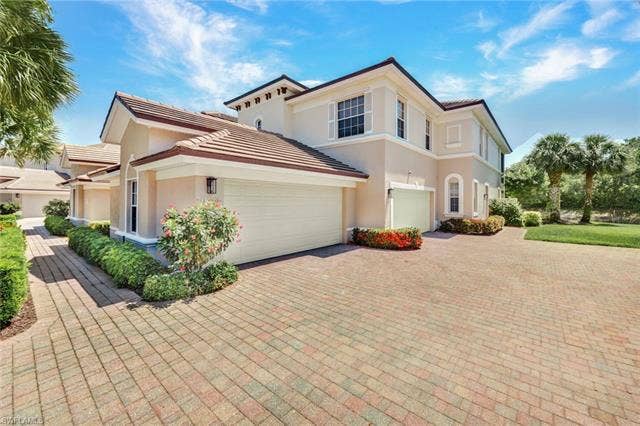 10060 Valiant Ct, #202, Miromar Lakes, FL 33913 Multi-story stucco exterior featuring a two-car garage, barrel tile roofing, and decorative window shutters