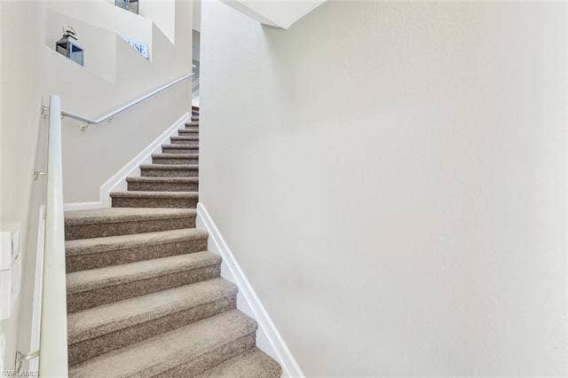 10060 Valiant Ct, #202, Miromar Lakes, FL 33913 Carpeted staircase with white risers and a contrasting gray handrail