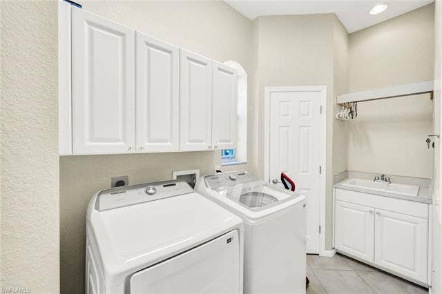 10060 Valiant Ct, #202, Miromar Lakes, FL 33913 Dedicated laundry room featuring white shaker-style cabinetry, a utility sink with a countertop, and recessed lighting