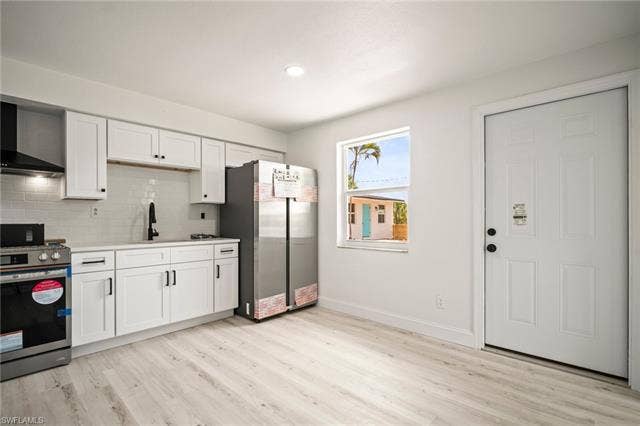 2316 Bayside St, Naples, FL 34112 Kitchen featuring appliances with stainless steel finishes, light wood-style flooring, decorative backsplash, white cabinets, and recessed lighting