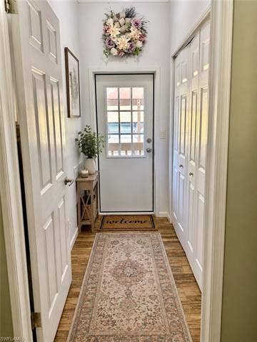 20472 Luettich Ln, Estero, FL 33928 Entryway featuring wood-finish flooring, a paneled door with glass inserts, and white bi-fold closet doors