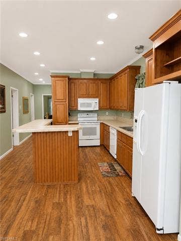 20472 Luettich Ln, Estero, FL 33928 Kitchen featuring wood-finish flooring, wood cabinetry, white appliances, a breakfast bar, and recessed lighting