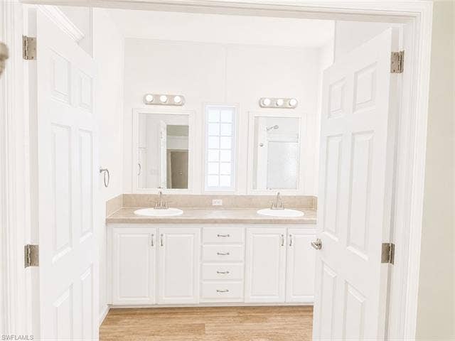 20472 Luettich Ln, Estero, FL 33928 Bathroom with a dual vanity featuring white cabinetry, integrated sinks, light-toned countertop, and individual mirrors with vanity lighting