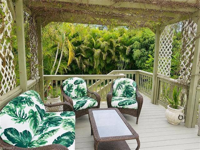 20472 Luettich Ln, Estero, FL 33928 Expansive outdoor deck featuring a light-toned wood-finish surface, a substantial wooden pergola overhead, and white lattice panels
