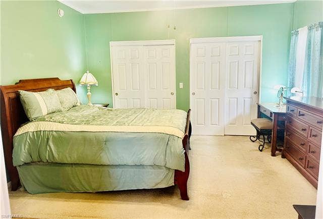 20472 Luettich Ln, Estero, FL 33928 Carpeted room featuring a light green wall finish, white bi-fold closet doors with panel detailing, and a white ceiling