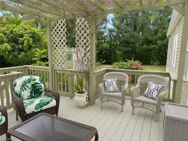 20472 Luettich Ln, Estero, FL 33928 Spacious outdoor deck featuring a wooden pergola, lattice accents, and perimeter railing