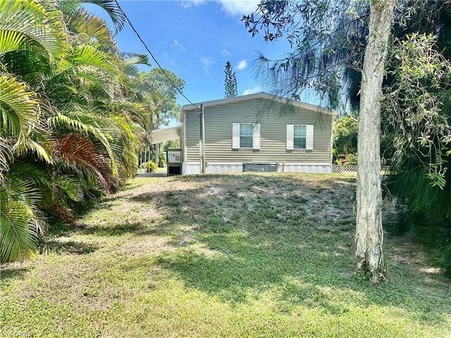 20472 Luettich Ln, Estero, FL 33928 Single-story residence featuring horizontal siding and white window shutters