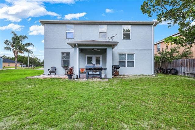 26701 Lincoln Ave, Bonita Springs, FL 34135 Expansive grass lawn with a two-story exterior featuring a covered patio