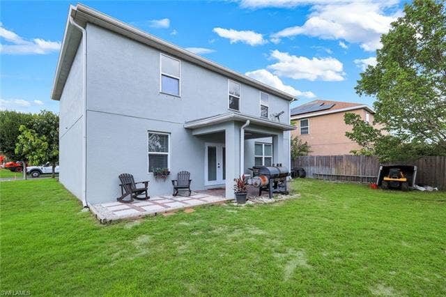 26701 Lincoln Ave, Bonita Springs, FL 34135 Spacious backyard featuring a covered patio with brick pavers, a substantial lawn area, and a privacy fence
