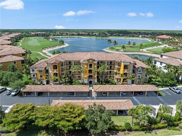 17921 Bonita National Blvd, #244, Bonita Springs, FL 34135 Mediterranean-style multi-story building featuring terracotta roof tiles, multiple balconies, and integrated carports